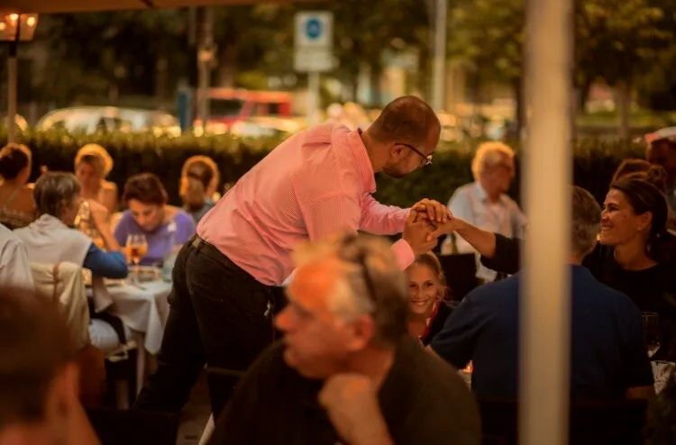 Biagio Salerno begrüßt Gäste vor der voll besetzten Terrasse des Ristorante Risotto