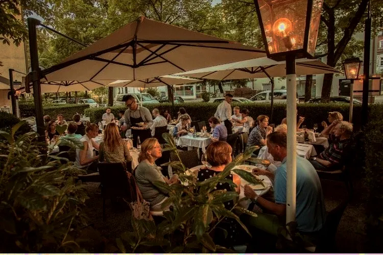Volle Terrasse des Ristorante Risotto an einem Sommerabend mit Gaslampe und Gästen